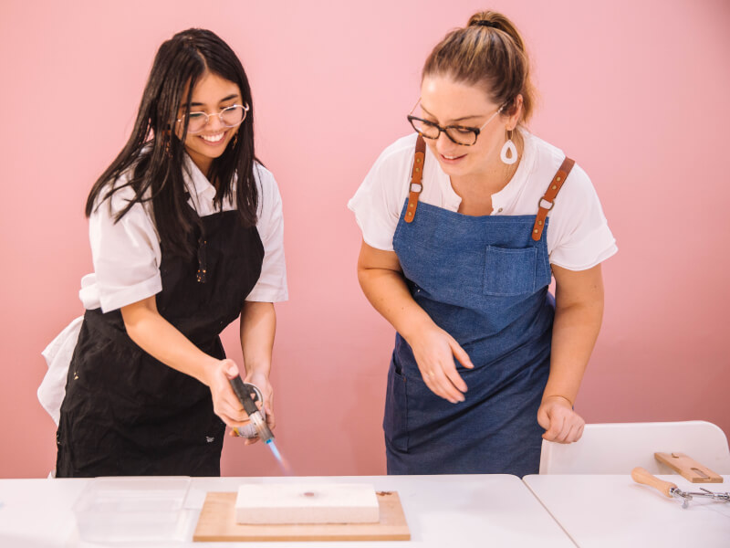 Teacher helping student use blowtorch to make DIY jewellery